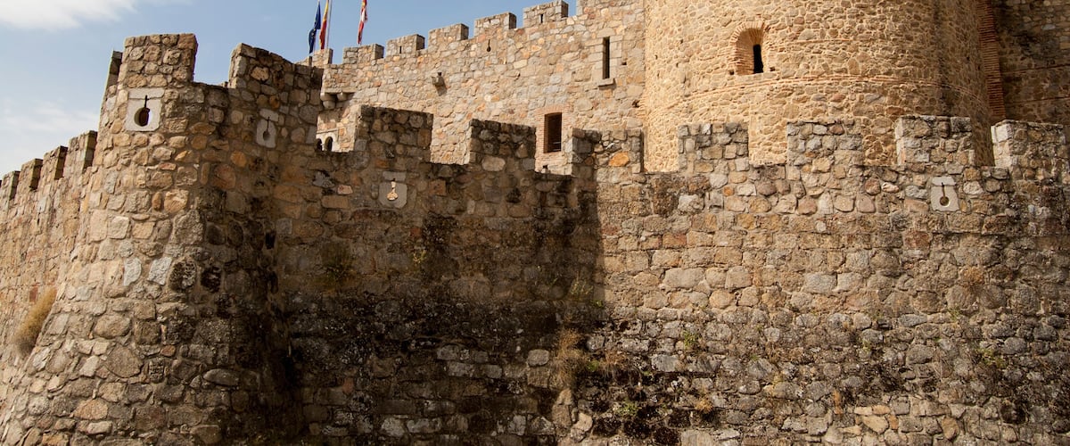 A historic stone castle with multiple towers and flags.