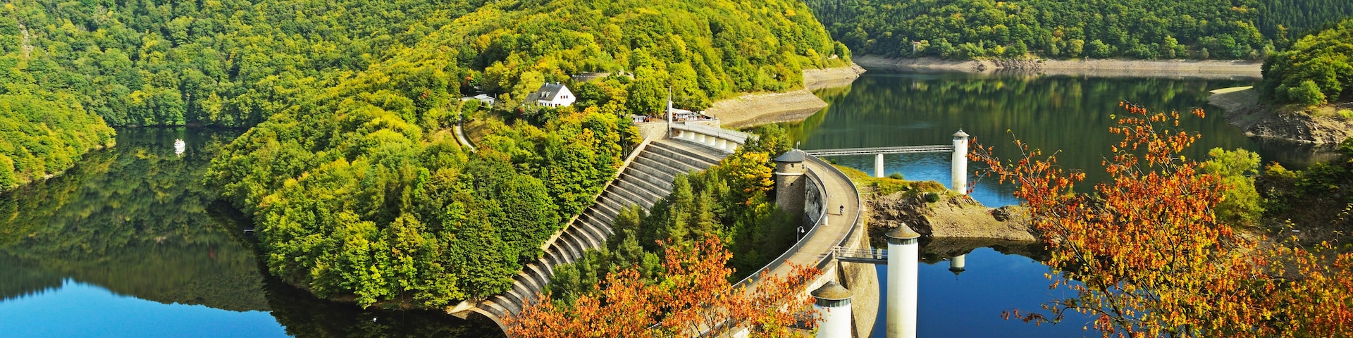 Ein Stausee mit Brücke, umgeben von üppigen grünen Hügeln und einem ruhigen See.