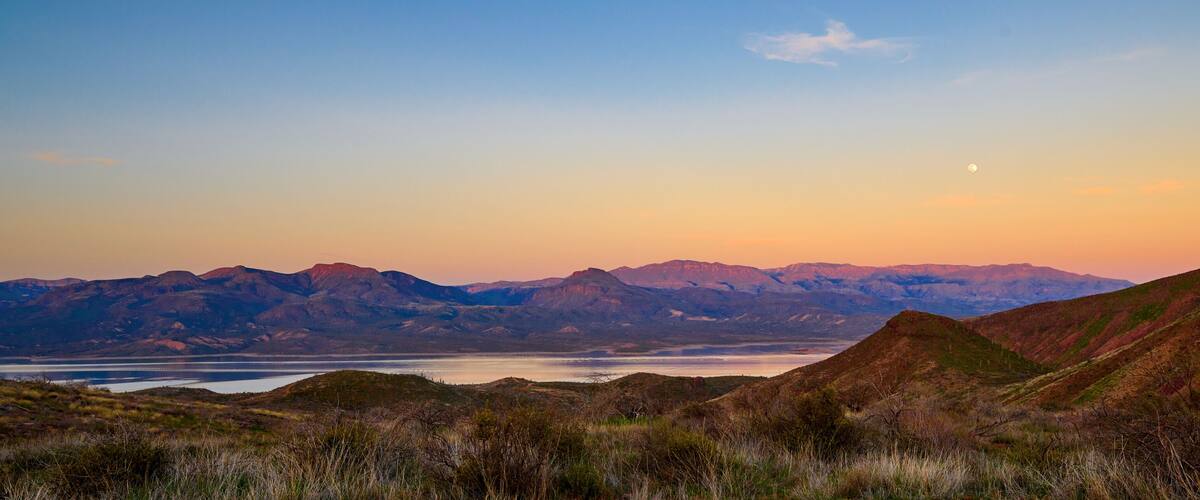 Evening view of Roosevelt Lake with full moon rising in the sky.
