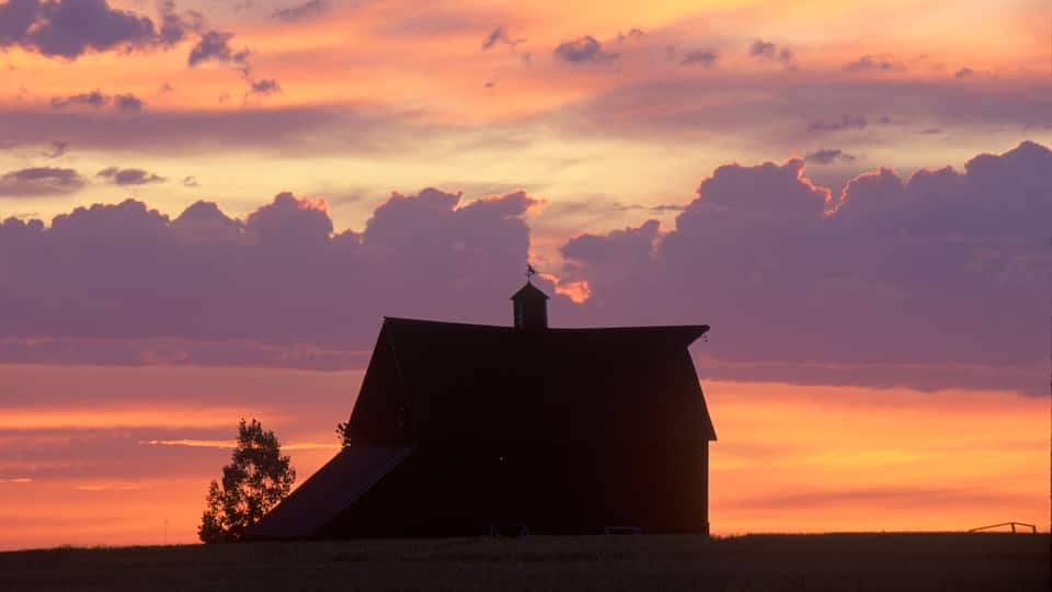 A barn silhouetted against a sunset sky.
