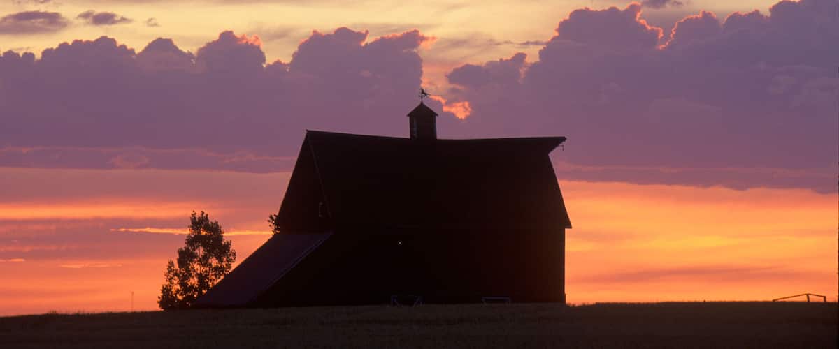 A barn silhouetted against a sunset sky.