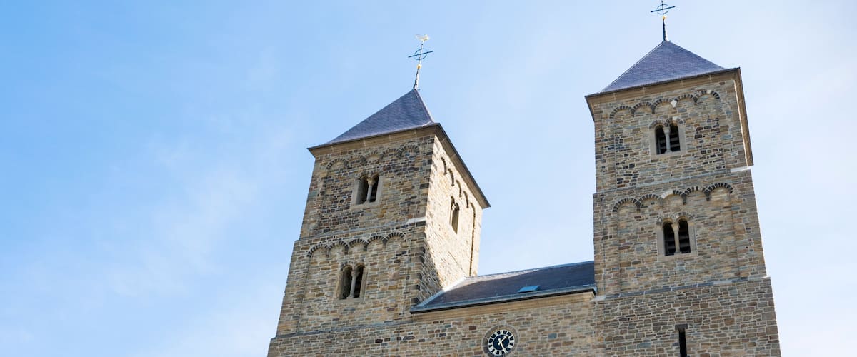 A historic stone tower with a clock and a weather vane.