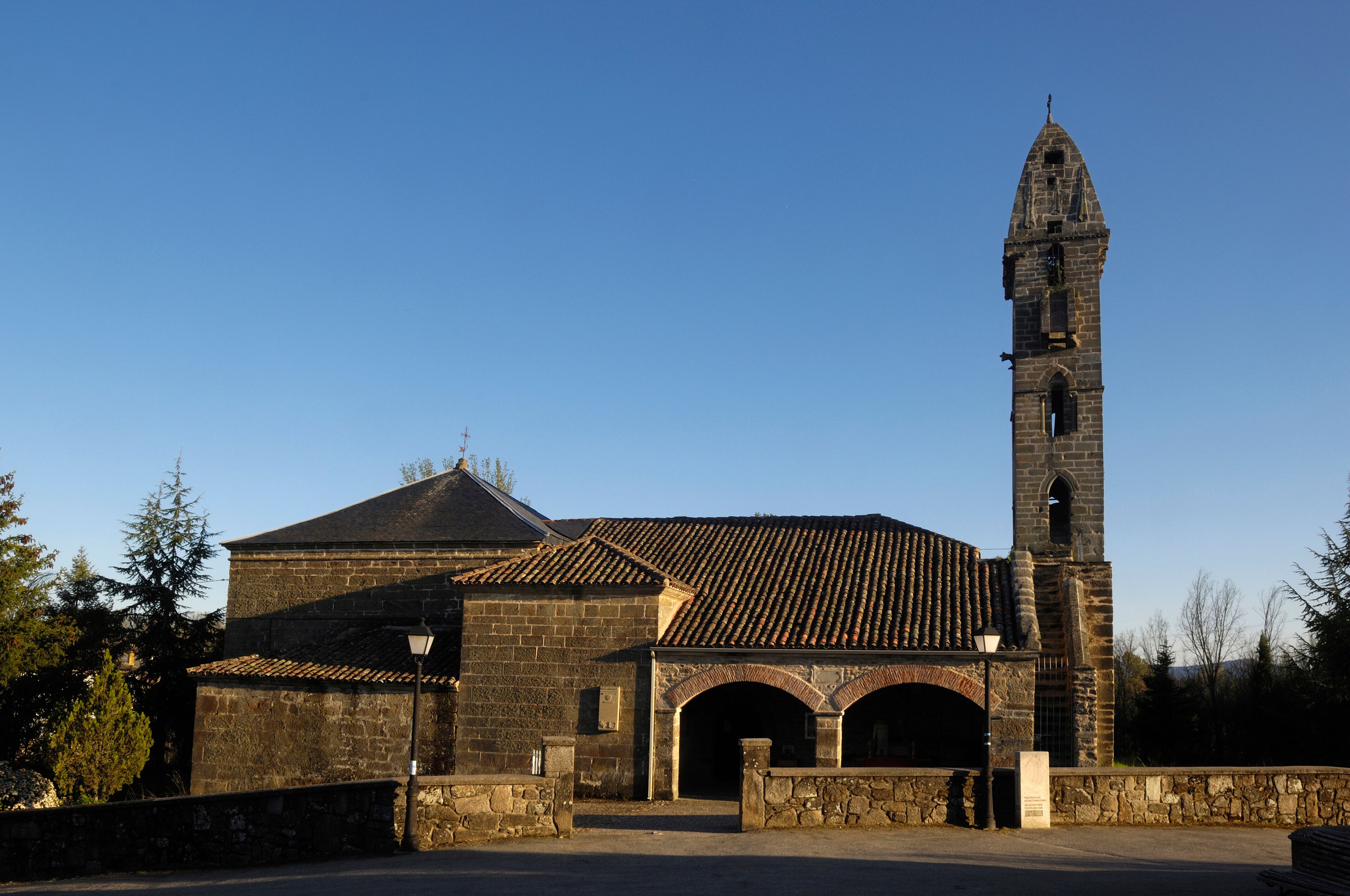 A historic church with a tall bell tower and a stone building with a tiled roof.