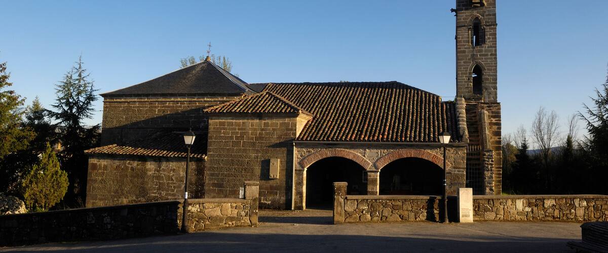 A historic church with a tall bell tower and a stone building with a tiled roof.