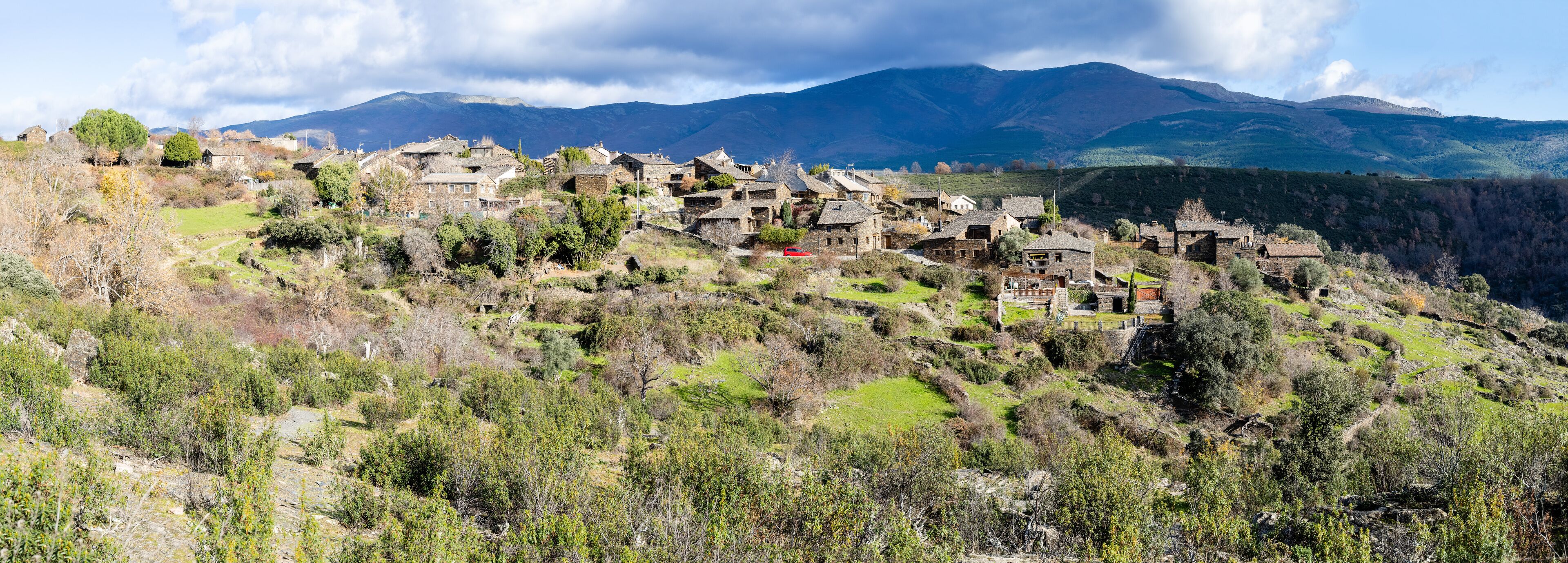 A village nestled in a valley with mountains in the background.
