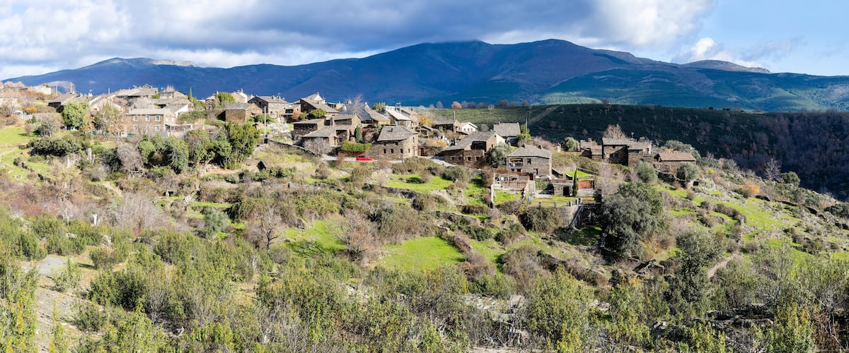 A village nestled in a valley with mountains in the background.