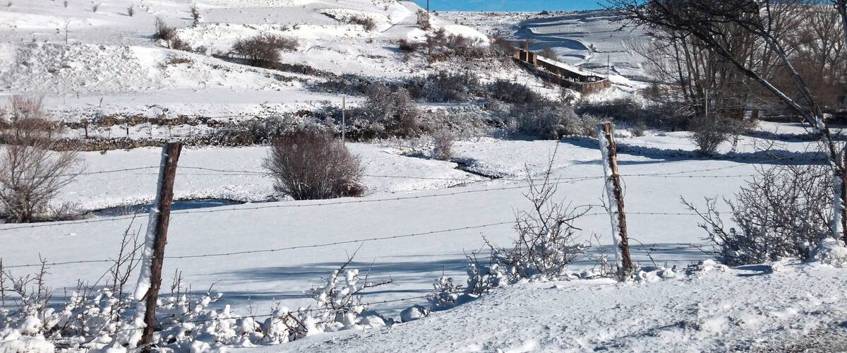 A snow-covered landscape with a castle on a hill and a clear blue sky.