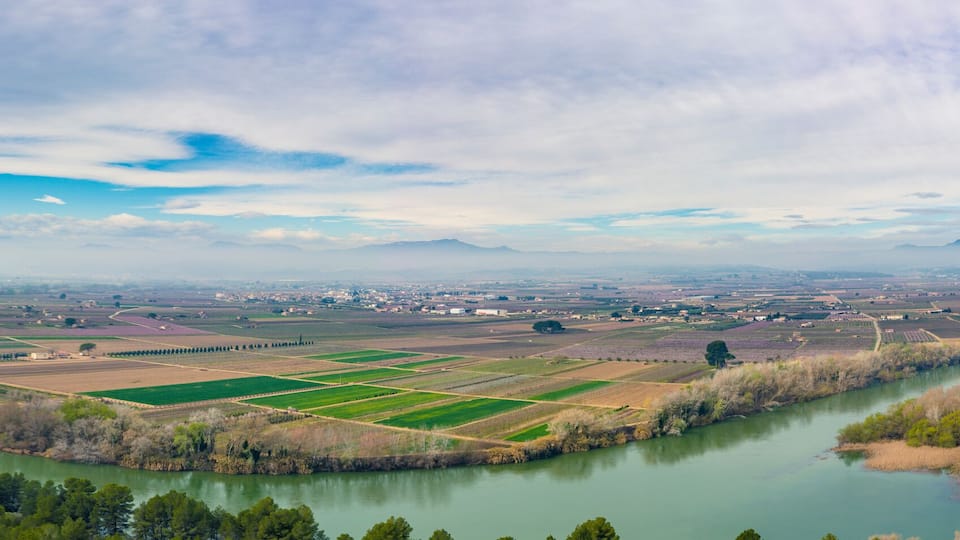A river winding through a valley with fields and a bridge.