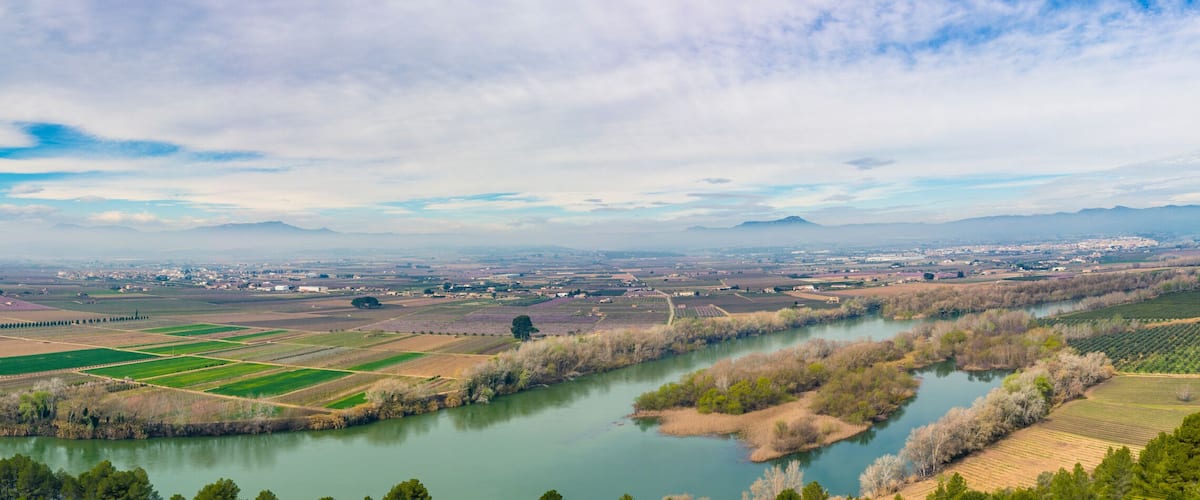 A river winding through a valley with fields and a bridge.