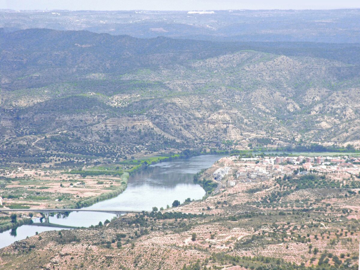 A river winding through a hilly landscape with scattered buildings.