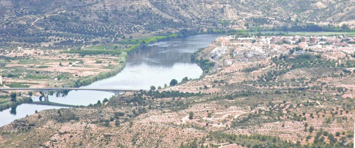 A river winding through a hilly landscape with scattered buildings.
