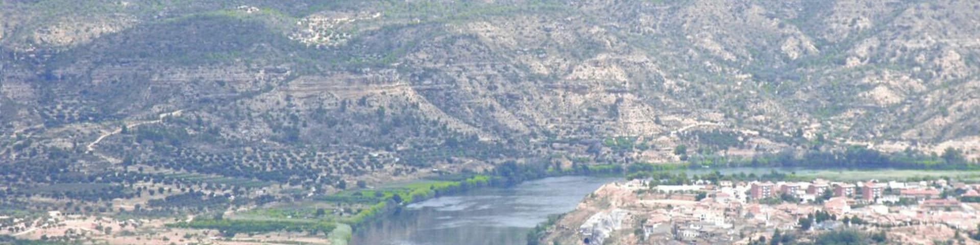 A river winding through a hilly landscape with scattered buildings.