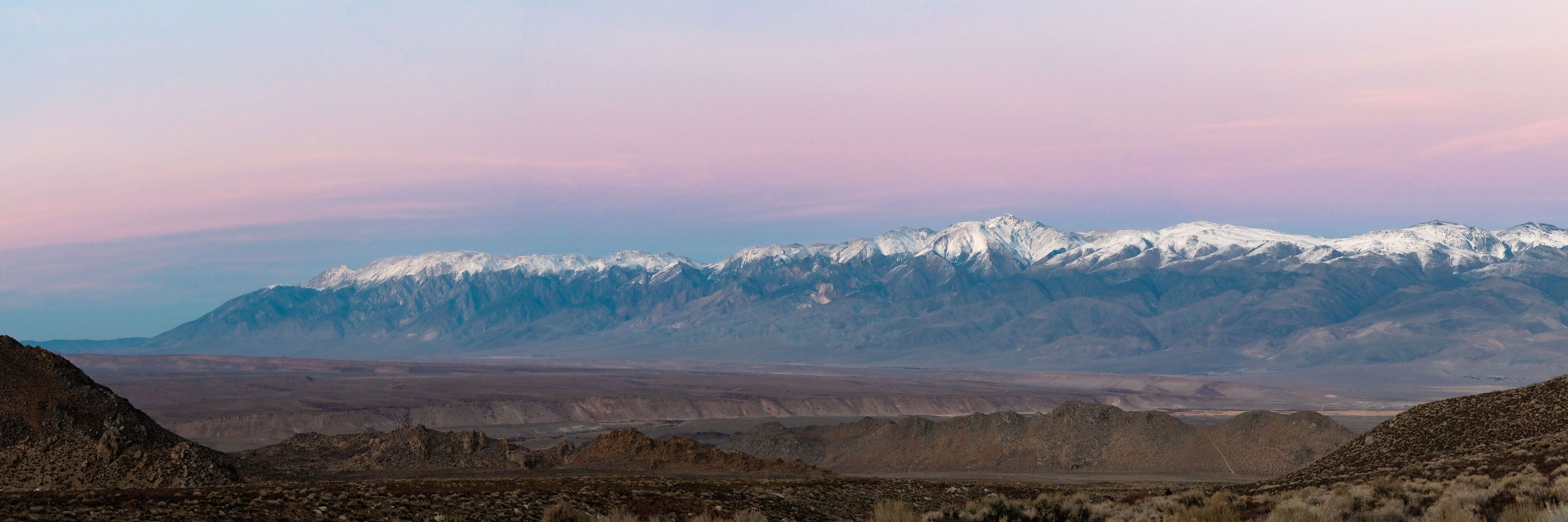 A mountain range with snow-capped peaks and a barren landscape.