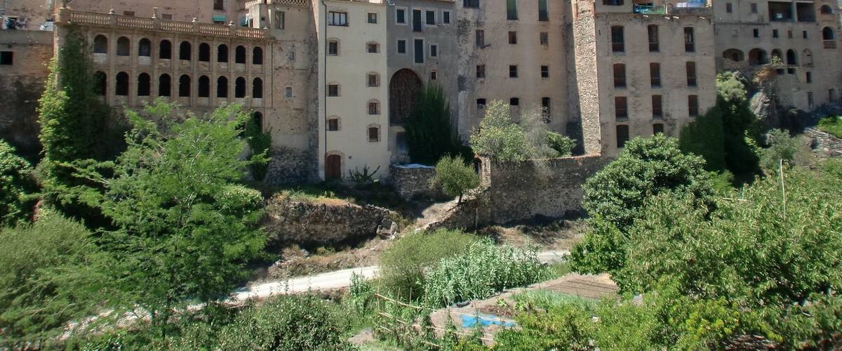 A historic town with a prominent clock tower, traditional architecture, and lush greenery.