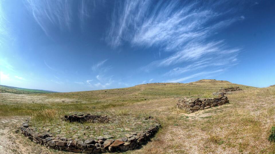 A stone circle on a grassy hill with a clear blue sky.