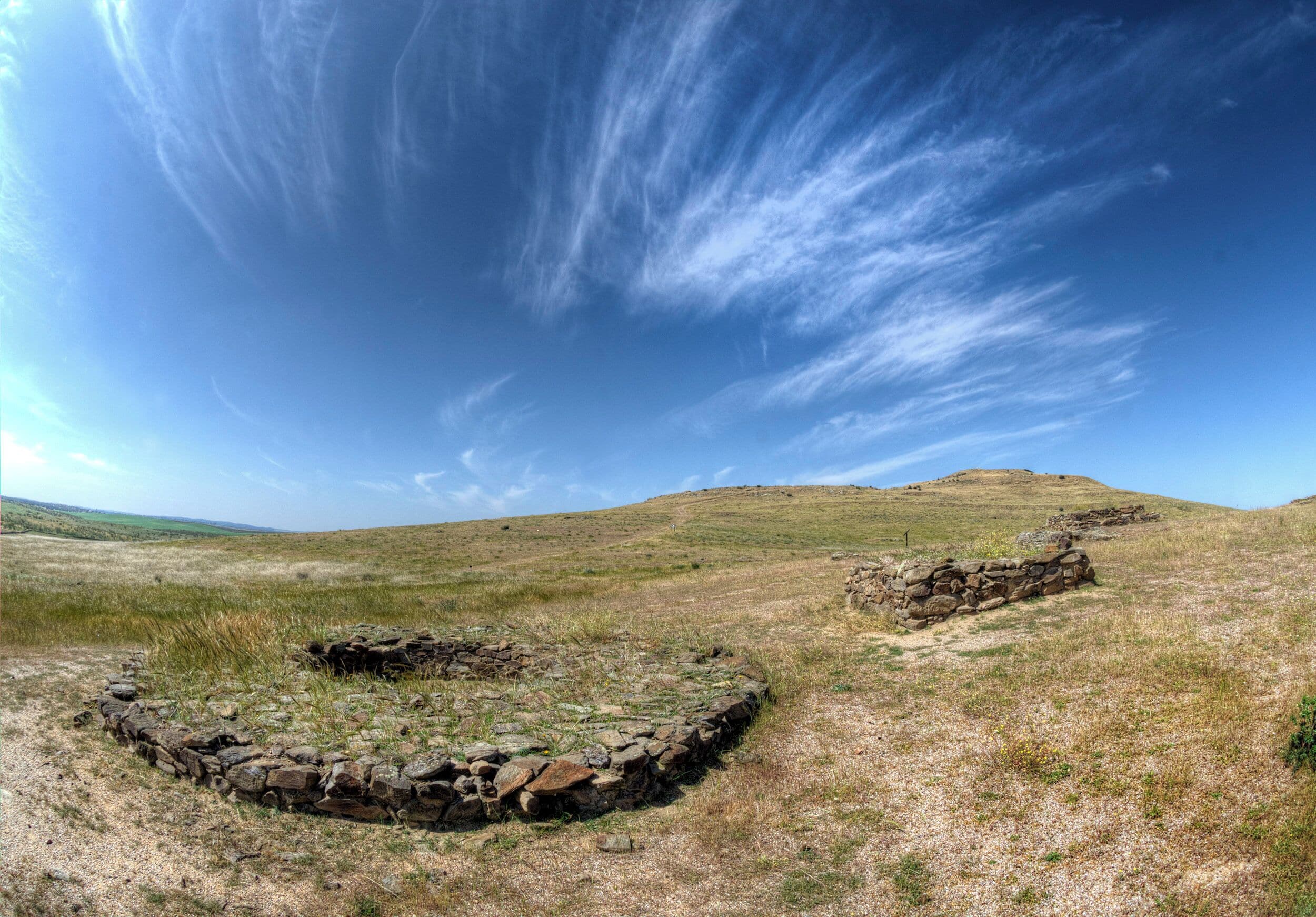 A stone circle on a grassy hill with a clear blue sky.