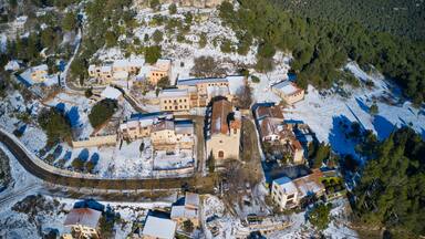 An aerial view of a snow-covered village with historic buildings and a church.
