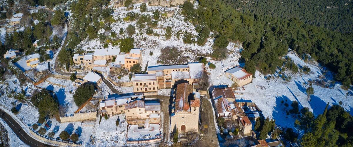An aerial view of a snow-covered village with historic buildings and a church.