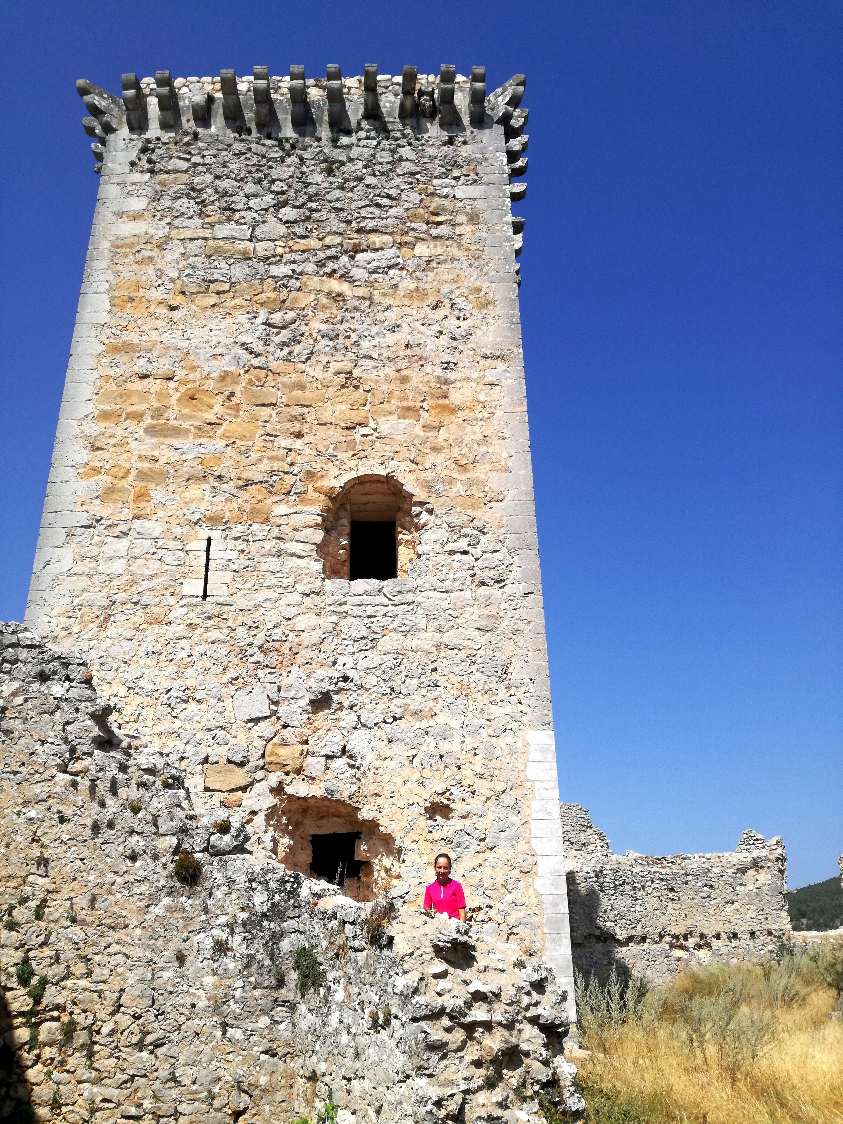 A stone tower with a small arched window and a person standing in front.