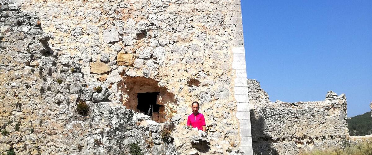 A stone tower with a small arched window and a person standing in front.