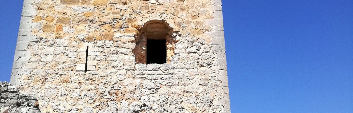 A stone tower with a small arched window and a person standing in front.