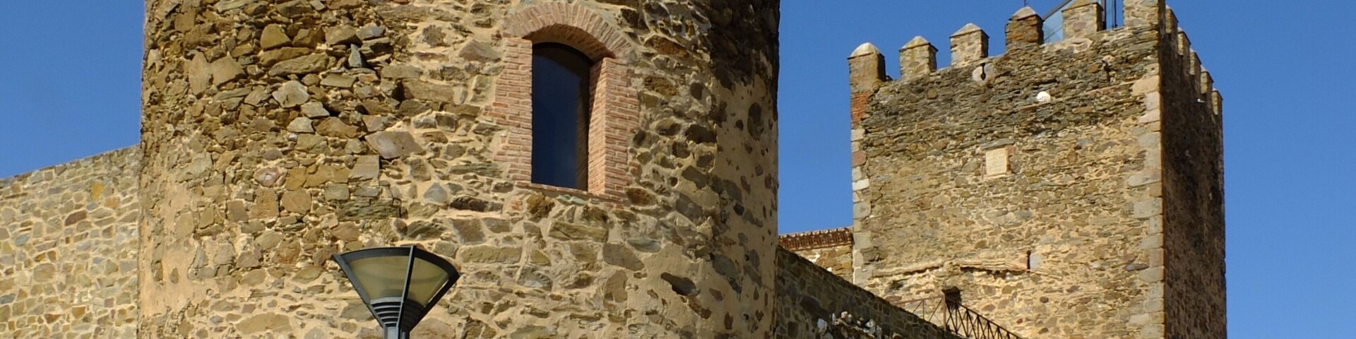 Un castillo de piedra histórico con una torre central y otra torre más pequeña adyacente.