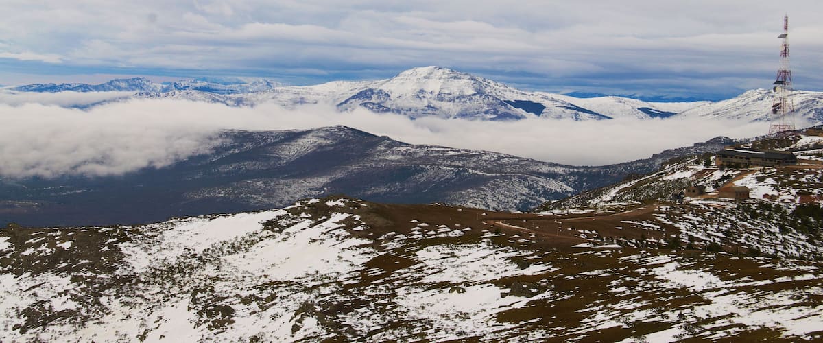 A snow-covered mountain range with a telecommunications tower on a hill.