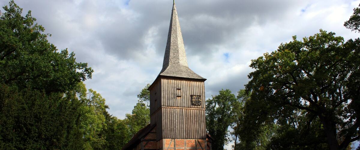 A church with a tall steeple, surrounded by trees.