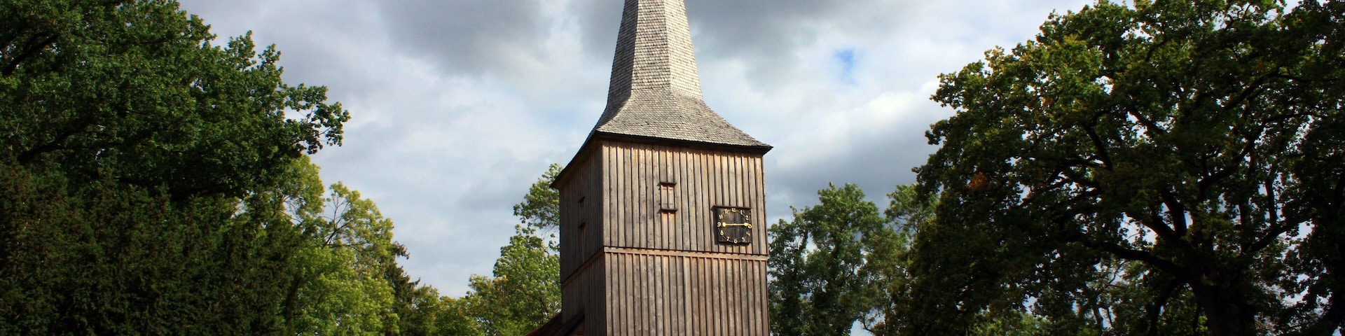 A church with a tall steeple, surrounded by trees.