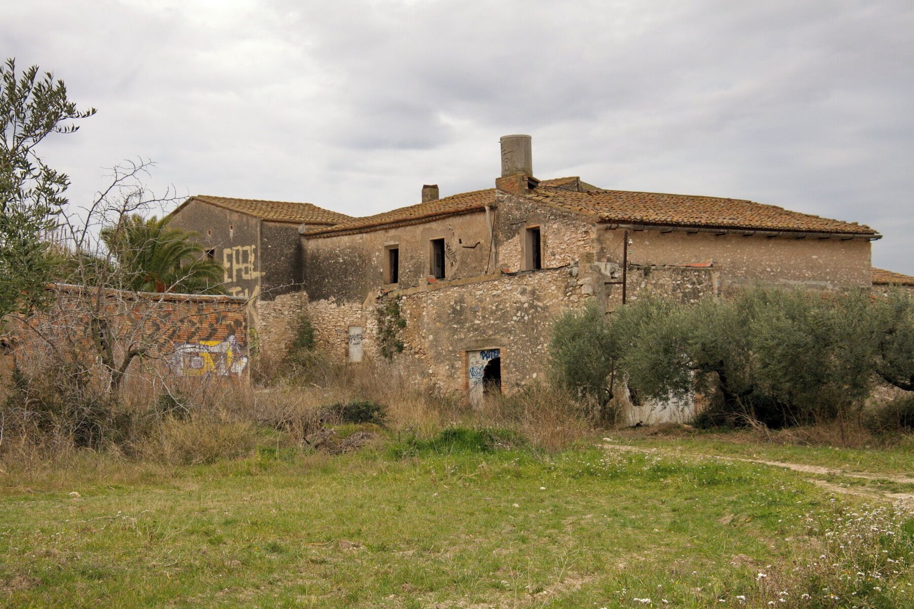 An abandoned building with a tiled roof and graffiti.