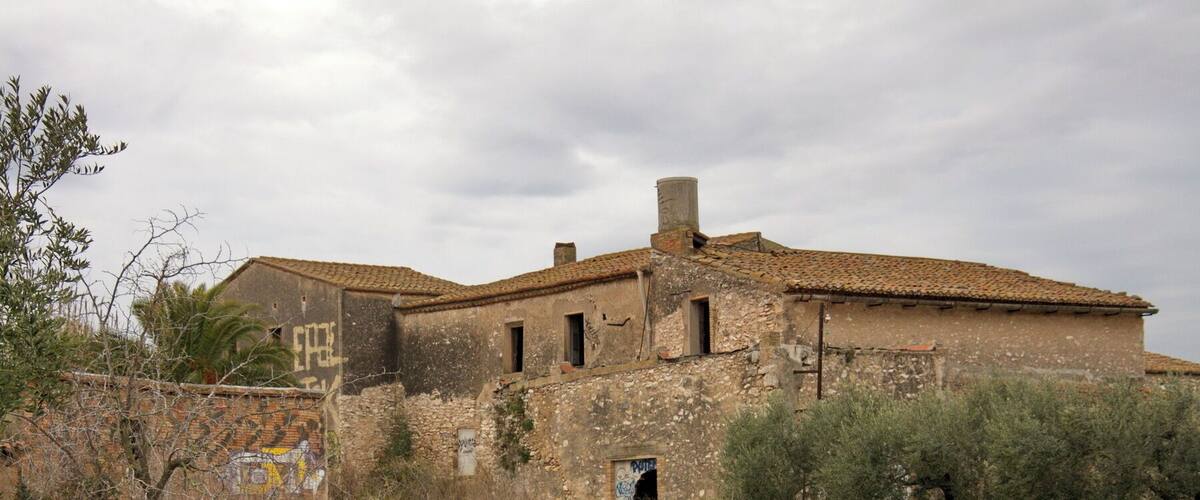 An abandoned building with a tiled roof and graffiti.