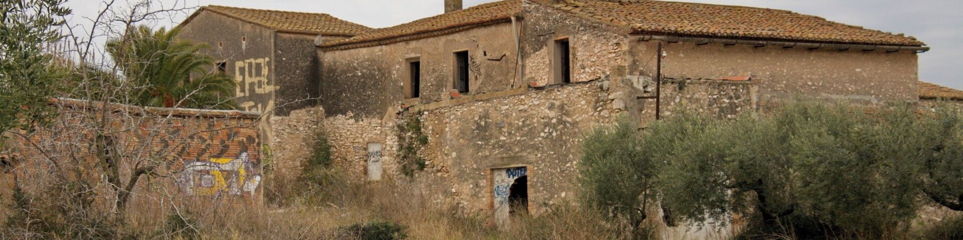 An abandoned building with a tiled roof and graffiti.