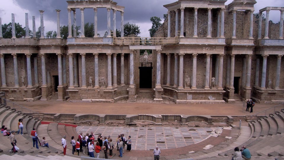 An ancient amphitheater with stone columns and a central stage.