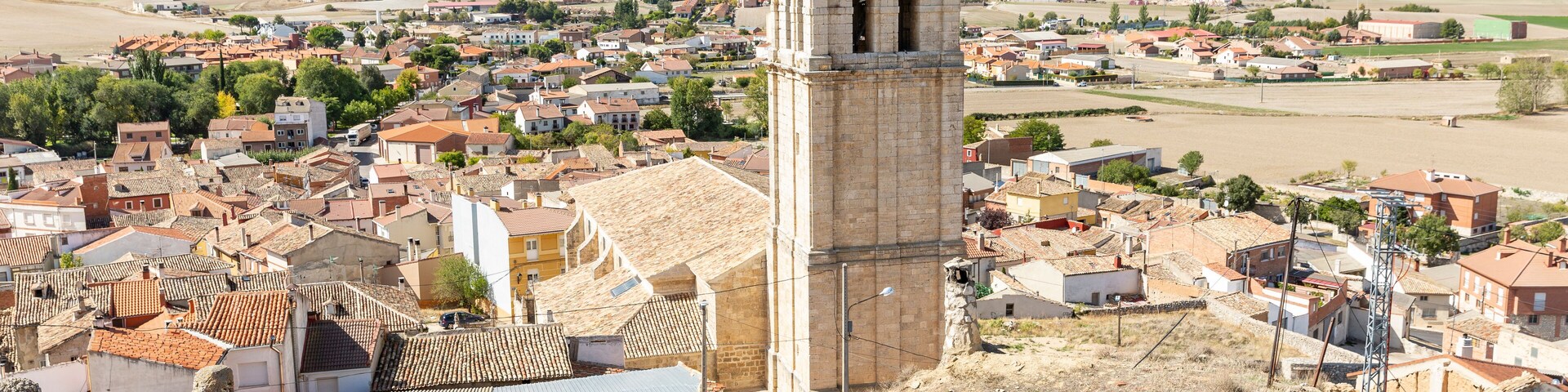 A historic town with a prominent tower, surrounded by terraced houses and fields.