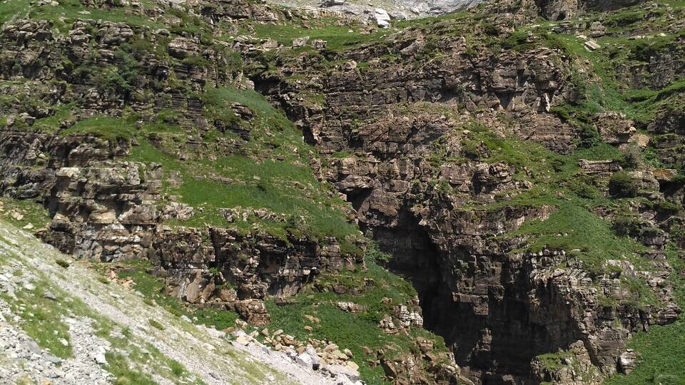 A mountainous landscape with a waterfall cascading down a rocky cliff.
