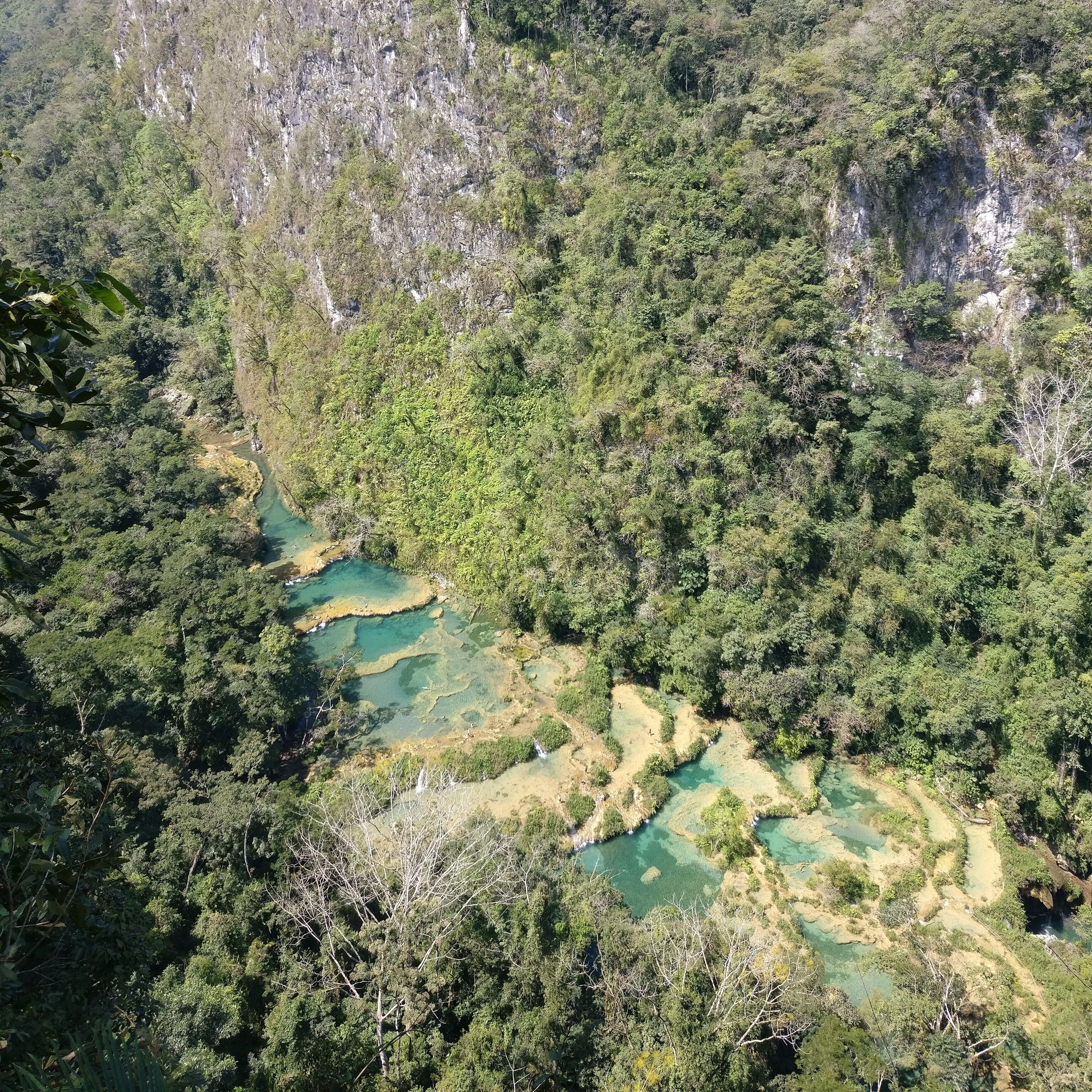 Semuc Champey is a place where rivers goes under. This place is a natural bridge with natural pools where you can swim. 

Photo is taken from El Mirador viewpoint.

More information about the place - https://nomadjoseph.com/everything-you-need-to-know-about-semuc-champey/