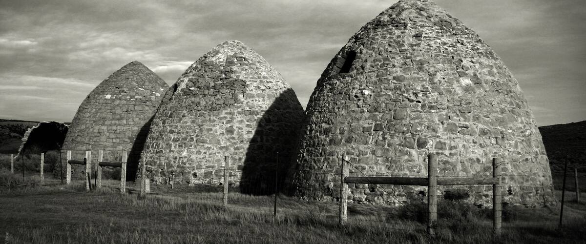 Three stone structures with pointed tops in a grassy field.