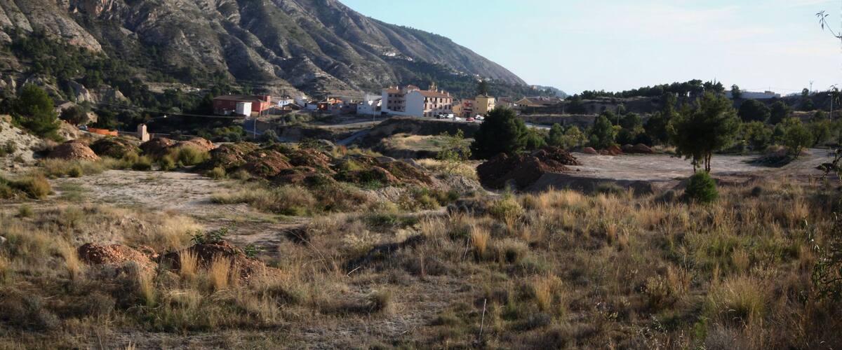 A mountainous landscape with a small settlement and sparse vegetation.