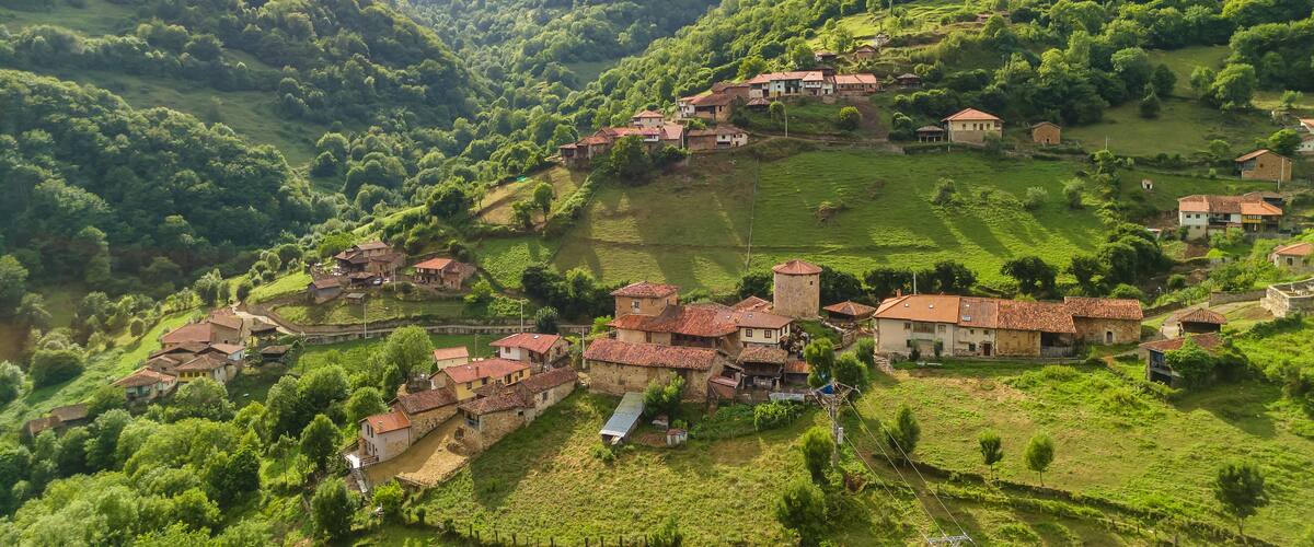 A village nestled in a valley surrounded by lush green hills.