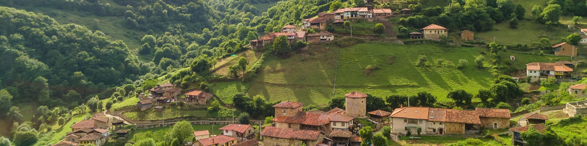 A village nestled in a valley surrounded by lush green hills.