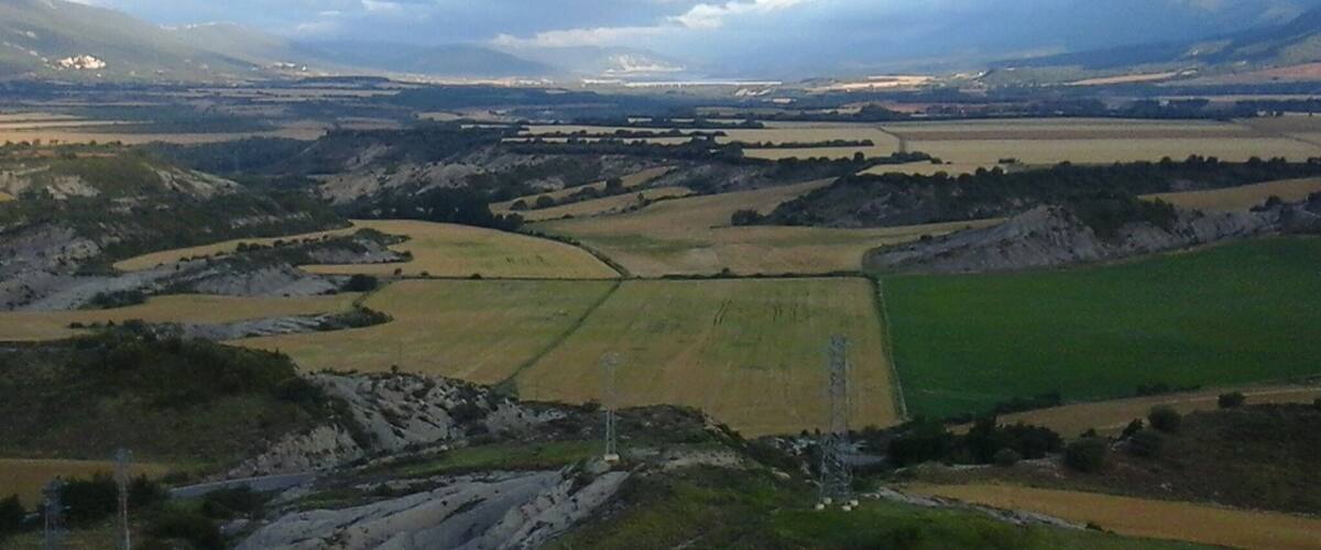 A rural landscape with rolling hills, fields, and a distant airport.
