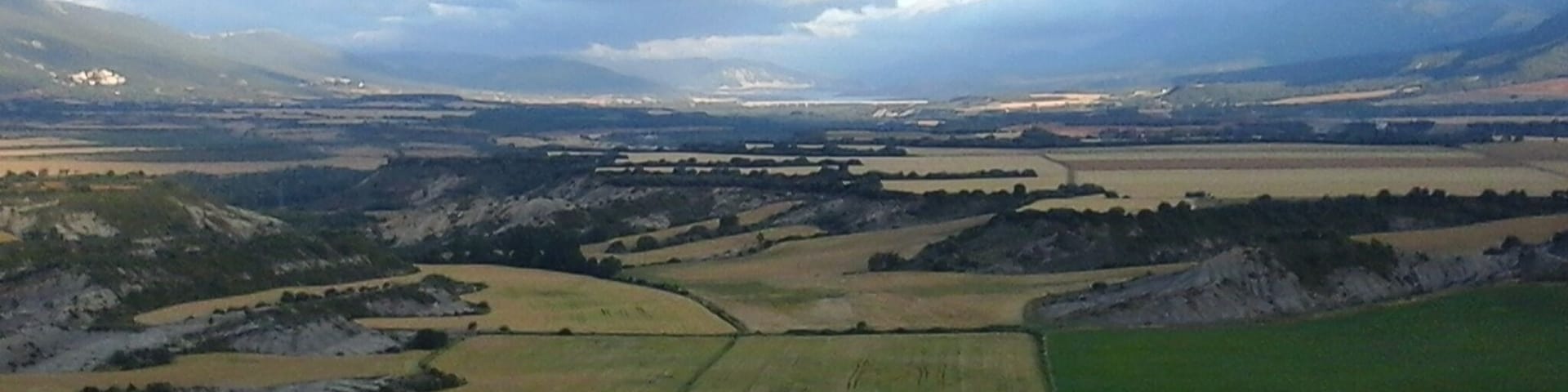 A rural landscape with rolling hills, fields, and a distant airport.