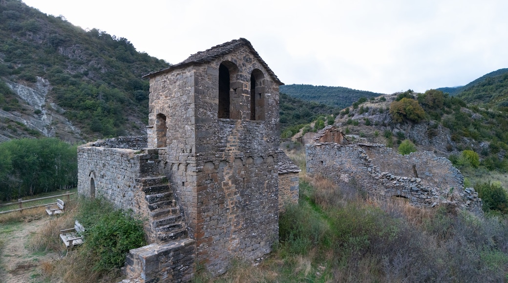 An ancient stone tower with arched openings, surrounded by rugged hills and sparse vegetation.