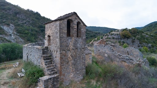 An ancient stone tower with arched openings, surrounded by rugged hills and sparse vegetation.