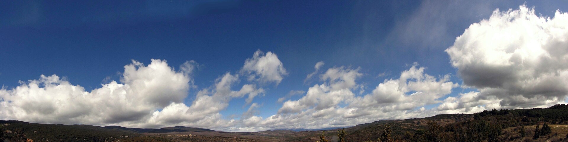 A mountainous landscape with a clear sky and scattered clouds.