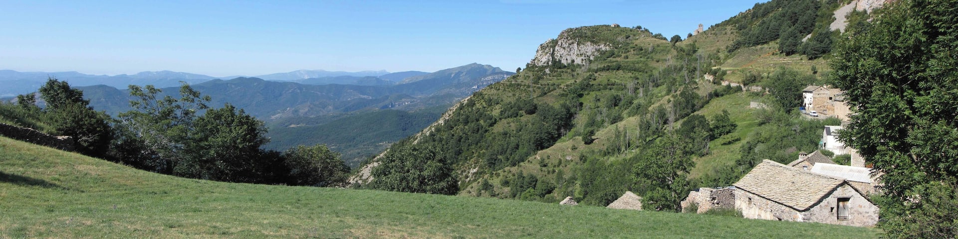 A mountainous landscape with a stone building on a hillside.
