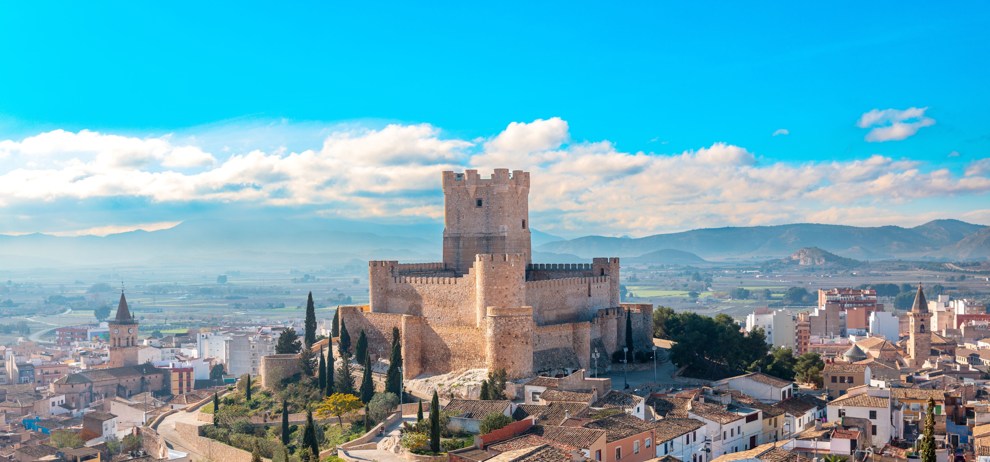 A historic castle surrounded by a cityscape with a clear sky.