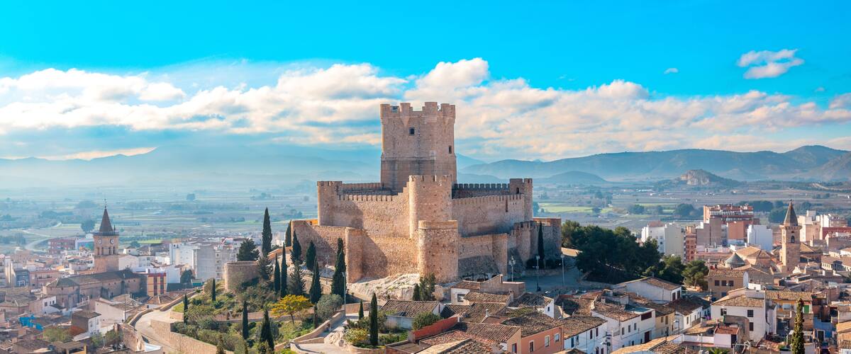 A historic castle surrounded by a cityscape with a clear sky.