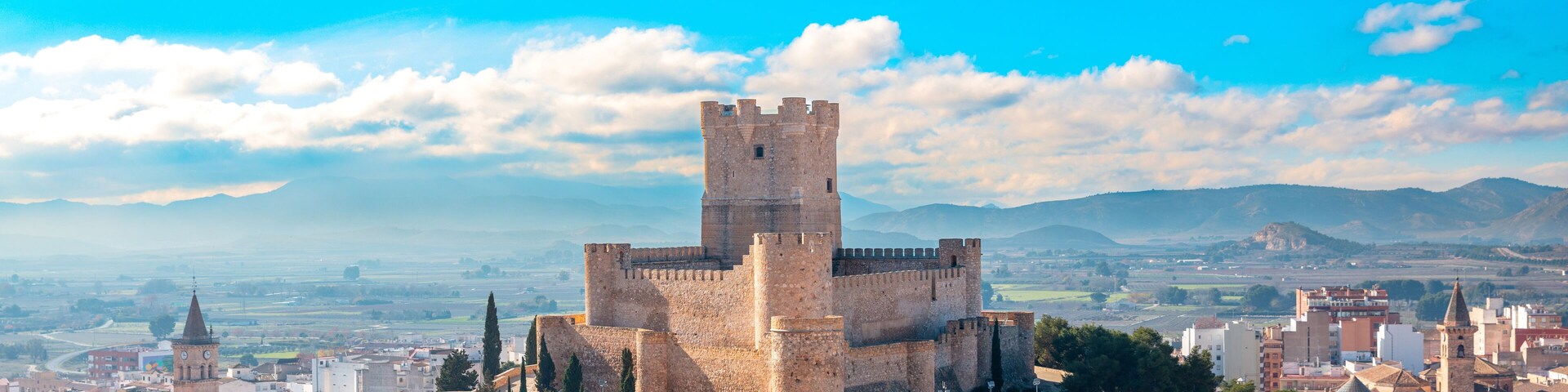 A historic castle surrounded by a cityscape with a clear sky.