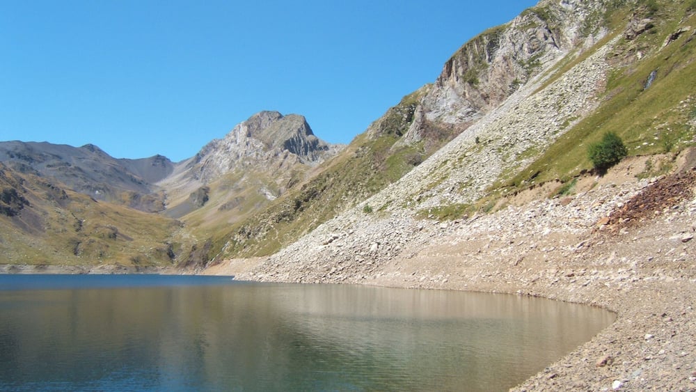 A mountain lake with rocky shores and a clear blue sky.